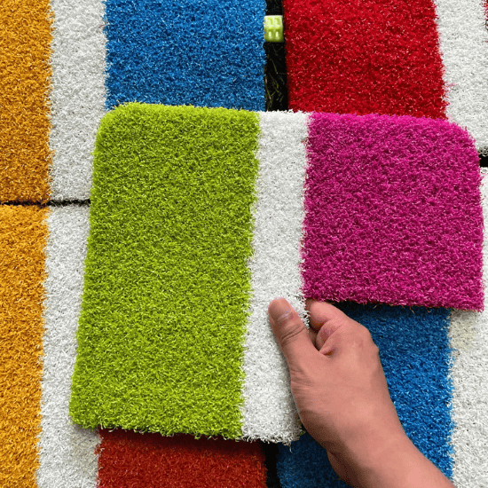 hand holding coloured artificial grass samples in green white and pink shades
