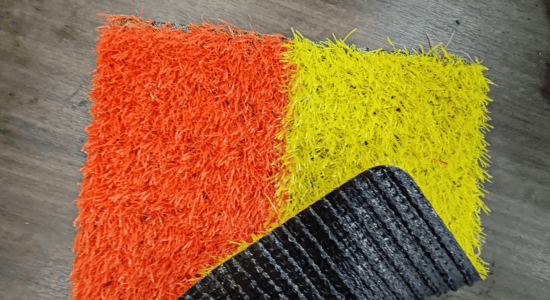 yellow and orange coloured artificial grass sample with black rubber backing