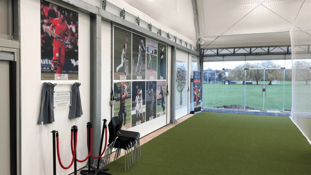 Indoor cricket turf with stumps and cricket themed artwork on the walls