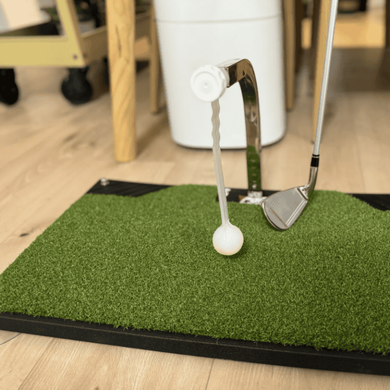 Indoor 2 close up of golf ball on tee with club ready for shot on synthetic grass practice mat indoors