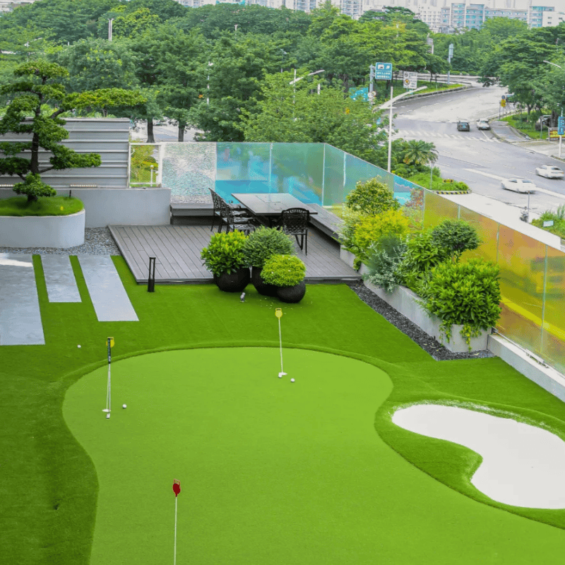 Outdoor 6 rooftop golf putting green with synthetic grass surrounded by plants and city view for urban outdoor practice