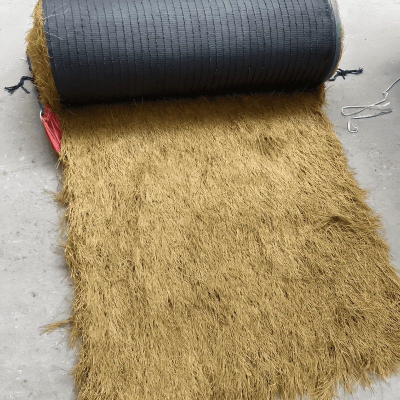 synthetic-thatch-roof-material-rolled-out-on-concrete-surface-showing-textured-fibers