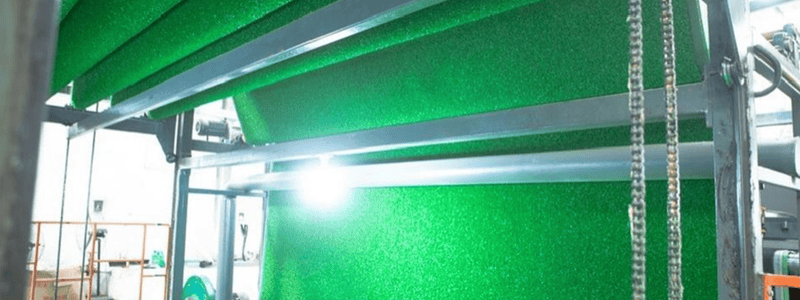 Somos líderes mundiales en soluciones de césped artificial 41 Láminas de césped artificial siendo procesadas en una máquina de fabricación.