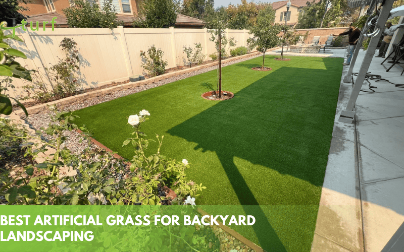 Cómo elegir el mejor césped artificial para cada uso 1 Paisajismo de patio trasero con césped artificial y árboles jóvenes cerca de una cerca blanca.