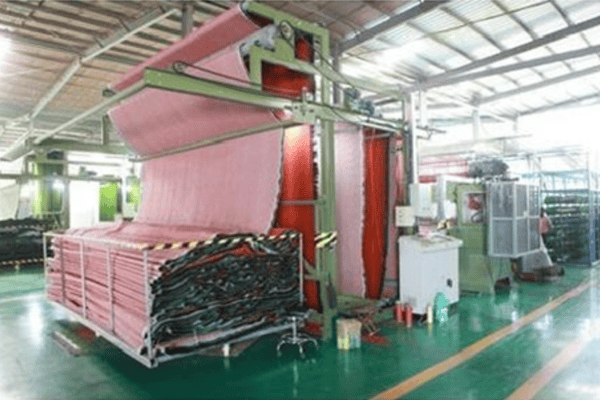 Somos líderes mundiales en soluciones de césped artificial 40 Línea de producción textil para césped artificial con rollos de material rojo y verde