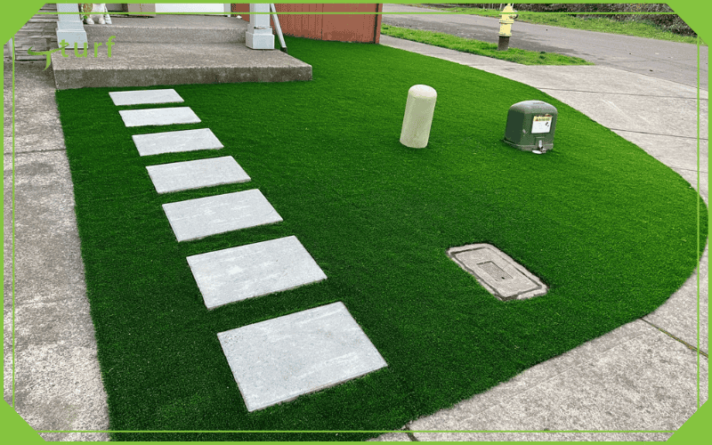 Patio delantero con césped artificial y escalones de hormigón en un espacio de estacionamiento residencial