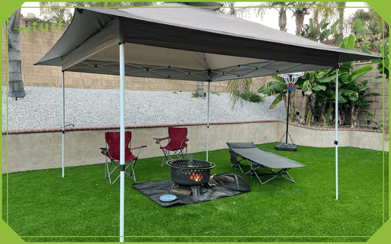 Outdoor canopy setup with chairs and fire pit on artificial turf in backyard