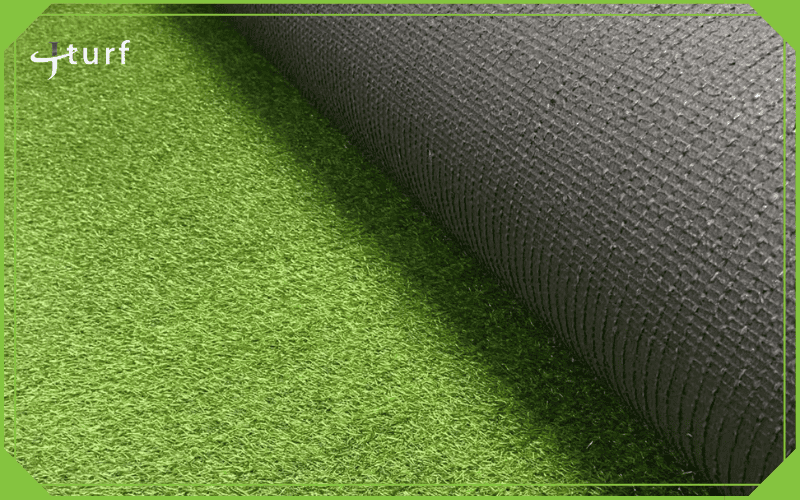 Rollo de césped artificial parcialmente desenrollado que muestra la textura del respaldo y el pelo de la fibra.