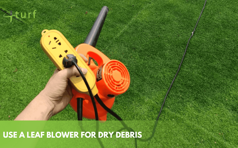 Using a leaf blower to remove dry debris from synthetic turf surface