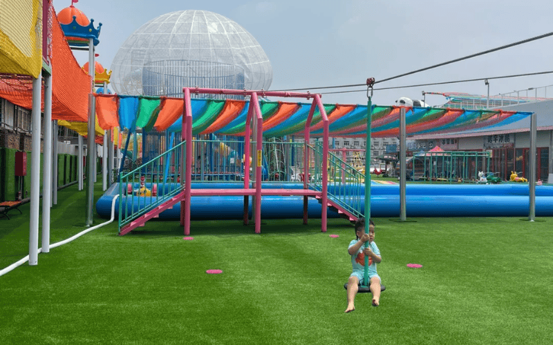 Acolchado de césped para áreas de juego 101 para superficies más seguras y suaves 3 Parque infantil con tirolinas sobre césped verde brillante