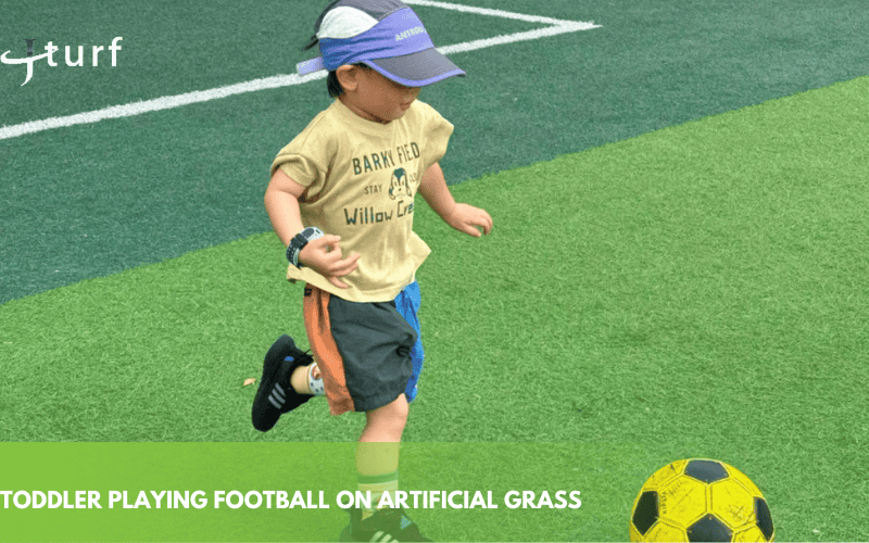 toddler playing football on artificial grass