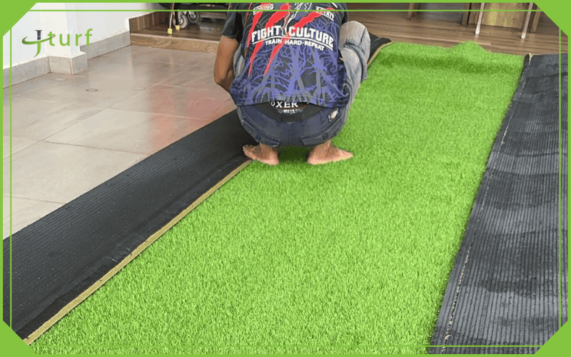worker installing artificial grass over concrete surface