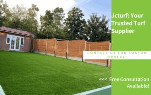 A green artificial turf lawn is shown next to a brick building, surrounded by wooden fencing and trees in the background.