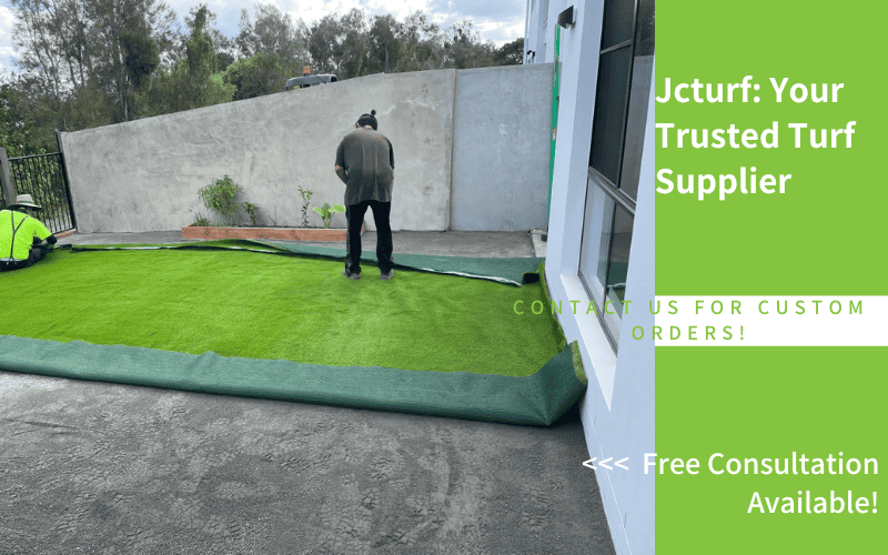 workers laying artificial grass under installation on concrete patio