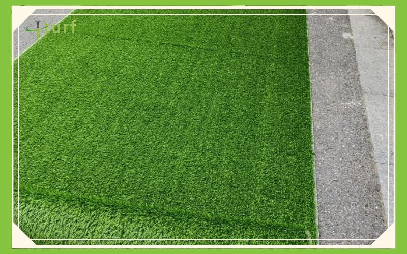 Una sección de césped artificial verde vibrante junto a un borde de hormigón.