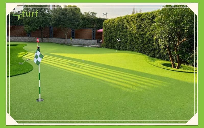 Un green verde vibrante con una bandera, rodeado de exuberante vegetación y luz solar que proyecta sombras.