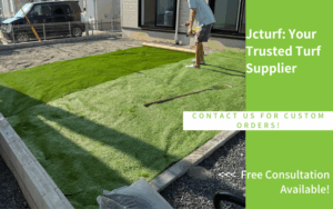 A person is laying down artificial grass on a prepared ground area next to a house.